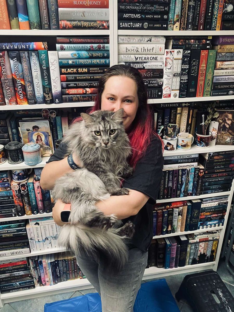 Melissa met Sansa de Maine Coon in haar armen, voor de boekenkast thuis